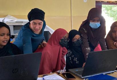 Staff Member Paige Roberts helps several girls with GIS workshop on computers